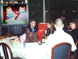 Shaun, Kelly and Joanie watching the slide show - On screen is a 3 year old Kelly with (If I had to guess) maybe her Aunt Vicky?